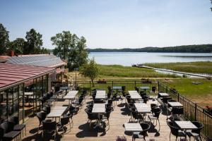 un mucchio di tavoli e sedie su una terrazza con un lago di Smålandsgården a Gränna