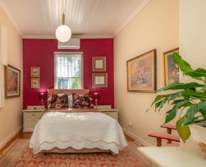 a bedroom with a bed and a red wall at Beautiful country house set in lush garden in Wellington +35 photos