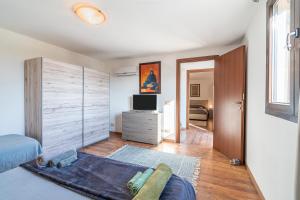 a bedroom with a bed and a dresser and a television at Villa Marta Maria con giardino in Siracusa