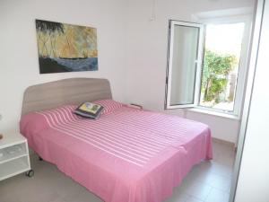 a pink bed in a white room with a window at Trilo Simonetta a Marcelli, con aria condizionata e posto auto in Marcelli