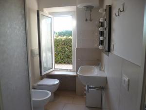 a bathroom with a toilet and a sink and a window at Trilo Simonetta a Marcelli, con aria condizionata e posto auto in Marcelli
