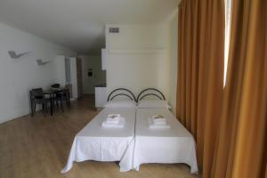 a bedroom with a bed with white sheets and a table at La Cordata Accommodation - Martinelli 55 - Mono 7 in Rho