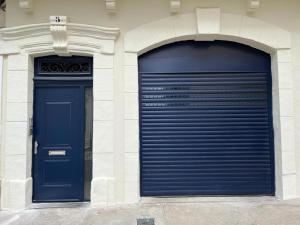 dos puertas de garaje azules en el lateral de un edificio en T3 pratique, Garage gratuit, Esprit Auber, en Béziers