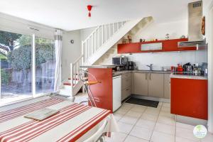 Biscarrosse bourg Duplex proche commerces 6 couchages في بيسكاروس: مطبخ به دواليب حمراء ودرج