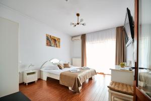 a white bedroom with a bed and a window at Pensiunea Kenza in Târgu-Mureş