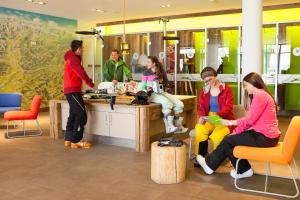 Un groupe de personnes assises autour d'un comptoir dans un magasin dans l'établissement Explorer Hotel Neuschwanstein, à Nesselwang