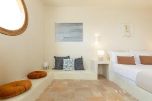 a white bedroom with a bed and a mirror at Villa Plaka 16 - 'The Boat' - Drepano, Nafplio in Dhrepanon