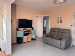 a living room with a couch and a flat screen tv at La CaMaNi in Quend-Plage
