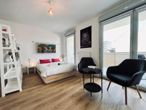 a bedroom with a bed and two chairs and a table at Bleuets studio cosy neuf terrasse proche centre in Reims