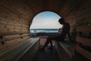 a woman sitting in a sauna looking out a window at Kuanza Nature Experience, Fajã do Belo in Fajã da Caldeira de Santo Cristo