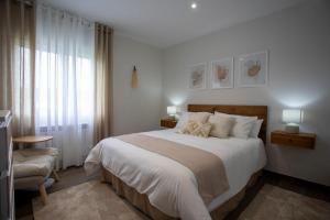 a bedroom with a large white bed and a chair at As Lavandas, Sober in Lobios