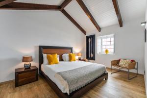 a bedroom with a bed and a chair at Kuanza Nature Experience, Fajã do Belo in Fajã da Caldeira de Santo Cristo