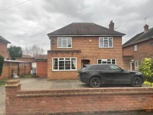 a black car parked in front of a brick house at Charming House with Garden - Sleeps 6 & Parking in West Drayton