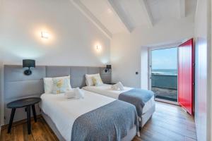 two beds in a room with a view of the ocean at Kuanza Nature Experience, Fajã do Belo in Fajã da Caldeira de Santo Cristo