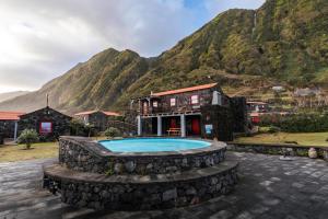 a resort with a swimming pool in front of a mountain at Kuanza Nature Experience, Fajã do Belo in Fajã da Caldeira de Santo Cristo