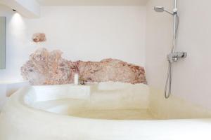 una vasca bianca in un bagno con parete di roccia di Villa Plaka 16 - 'The Cave' - Drepano, Nafplio a Drepano
