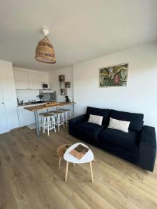 Una sala de estar con un sofá azul y una cocina. en Studio cosy au porte de l ocean, en Biscarrosse 16 fotos más