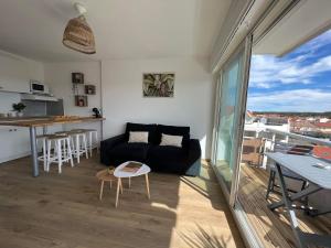 a living room with a couch and a kitchen at Studio cosy au porte de l ocean in Biscarrosse