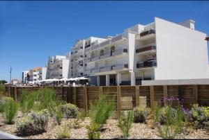 a building with a fence and flowers in front of it at Studio cosy au porte de l ocean in Biscarrosse