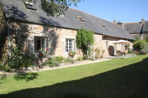 une maison en pierre avec une cour en gazon devant elle dans l'établissement Résidence CoatArmor, à Tonquédec