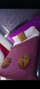 a bedroom with a purple bed with pillows and ties at Complexe A8CLOS in Douala