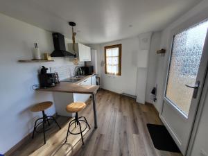 a kitchen with a table and two stools in a room at Le Grangeon in Belley