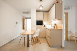 a kitchen with a wooden table and white chairs at La Suite d'Oscar l New, Terrace l Shellter Rentals in Saint-Tropez