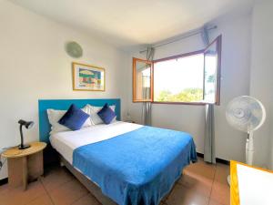 a bedroom with a bed with blue sheets and a window at Le Tournesol in Saint-Gilles-les-Bains