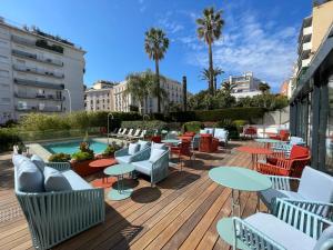 une terrasse avec des tables et des chaises ainsi qu'une piscine dans l'établissement Hôtel Le Canberra, à Cannes