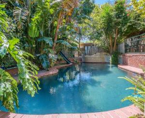 a swimming pool in a backyard with palm trees at Sacred Mountain Lodge in Noordhoek