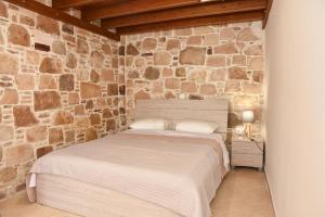 a bedroom with a bed in a stone wall at Kentos Charming Stone Escape Near Fishing Harbor in Katarráktis