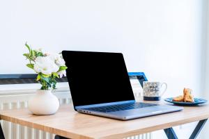 a laptop on a wooden table with a vase of flowers at Elstree Luxury Hse Contractors, Family, Industrial Area Harry Porter in Hemel Hempstead