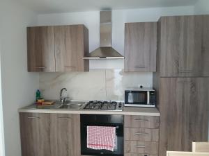 a kitchen with wooden cabinets and a stove and a microwave at MaGa House in Catania