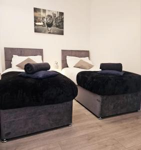 two beds with black covers in a bedroom at Hidden pearl in Gorleston-on-Sea