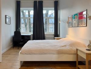 a bedroom with a bed and a desk and windows at Stepono Apartment in Vilnius