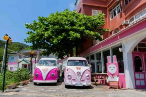 dos autos rosados y blancos estacionados frente a un edificio en Evening Sun B&B en Green Island