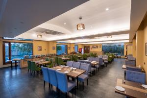 a restaurant with wooden tables and chairs and windows at DLS Forest Vines Resort in Belparāo