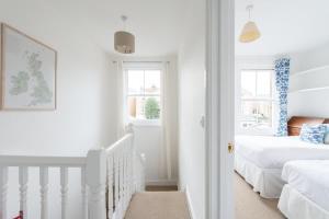 Un dormitorio blanco con dos camas y una escalera. en Beken House, en Cowes 7 fotos más