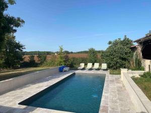a swimming pool with lounge chairs in a backyard at Lavande in Lauzun