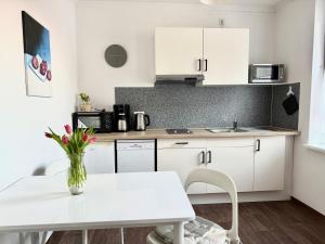 a kitchen with white cabinets and a table with a vase of flowers at Ferienwohnungen an der Weser in Bremerhaven