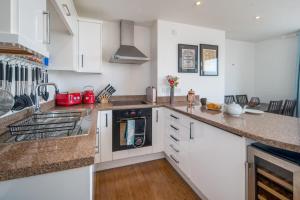a kitchen with white cabinets and a stove at Composers apartment in Cowes