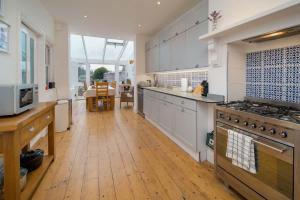 een grote keuken met witte kasten en een houten vloer bij Firefly House in Cowes