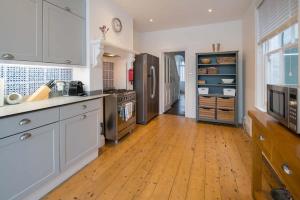 een keuken met witte kasten en een houten vloer bij Firefly House in Cowes