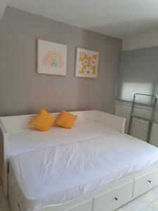 a white bed with two orange pillows on it at Modern apartment in Paleo Tsifliki