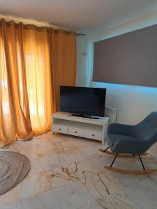 a living room with a television and a chair at Modern apartment in Paleo Tsifliki
