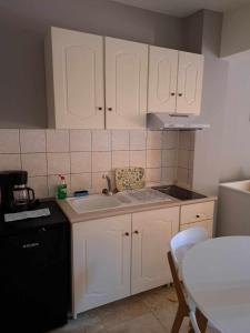 a kitchen with white cabinets and a sink and a table at Modern apartment in Paleo Tsifliki