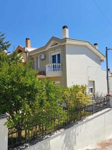 a white house with a fence in front of it at Modern apartment in Paleo Tsifliki