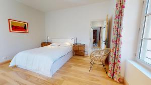 a white bedroom with a bed and a window at Le Moulin de la Cigogne in Saint-Vincent-Rive-dʼOlt