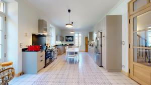 a large kitchen with white cabinets and a tile floor at Le Moulin de la Cigogne in Saint-Vincent-Rive-dʼOlt