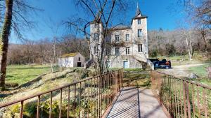an old house on a hill with a car on a bridge at Le Moulin de la Cigogne in Saint-Vincent-Rive-dʼOlt